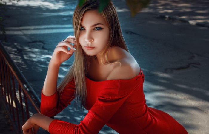 Woman in red dress with blonde hair and blue eyes outdoors