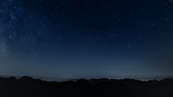 Starry night sky over silhouetted mountains