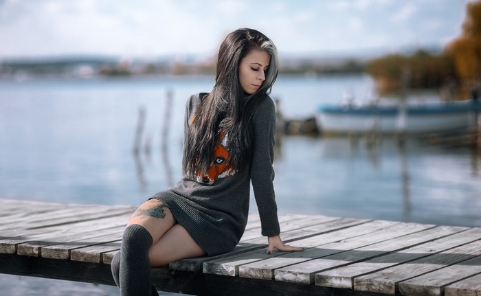 Woman with tattoo sitting on a wooden pier