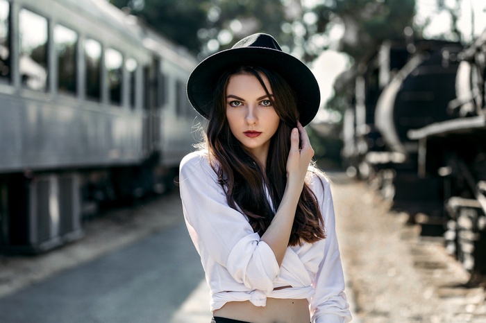 Woman in hat and white shirt near trains