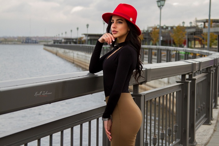 Woman in red hat and black top by the water