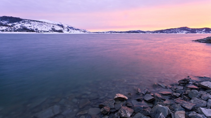 Snowy mountains and a lake at sunset