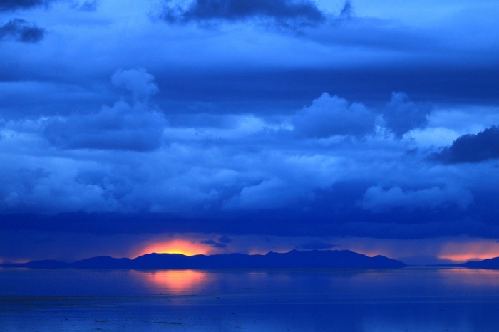 Blue sky over calm sea with island silhouette at sunset