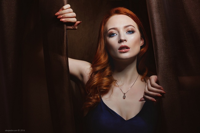Woman with red hair peeking through curtains