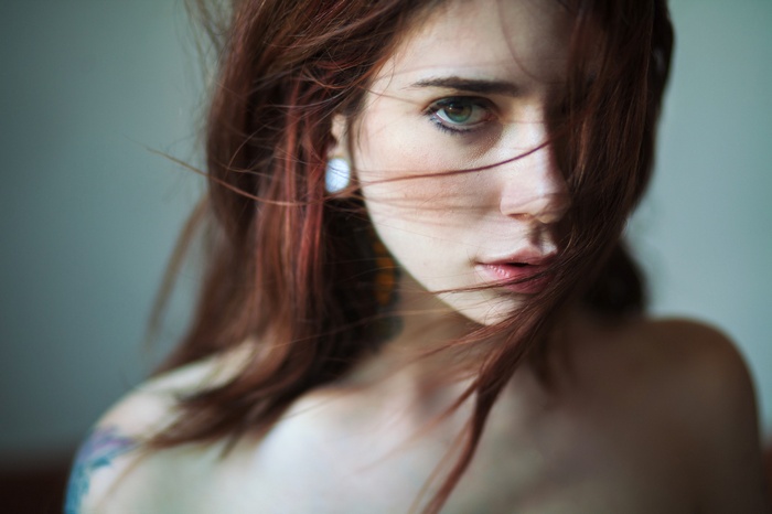 Woman with red hair and green eyes, hair in face
