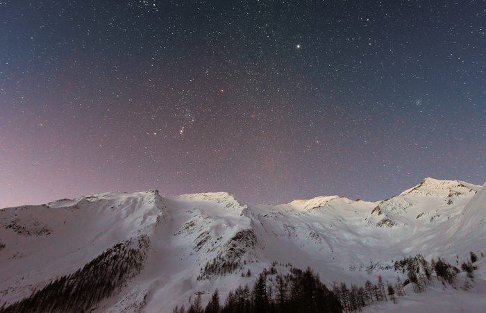 Snowy mountains under a starry night sky