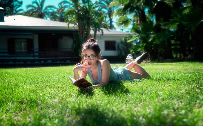 Woman reading a book on the grass outdoors
