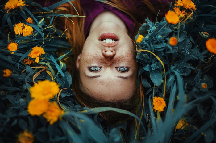 Woman with freckles lying in flowers