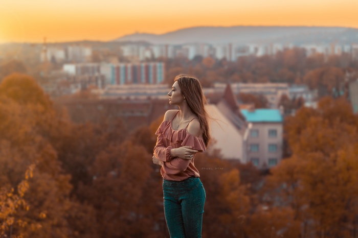 Woman in pink top and jeans with city background