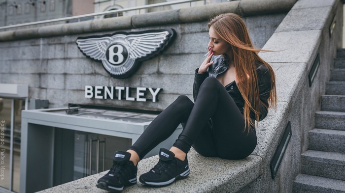 Woman smoking in front of Bentley building