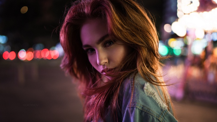 Woman with red hair in denim jacket at night