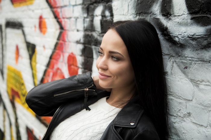 Angelina Petrova leaning against graffiti wall