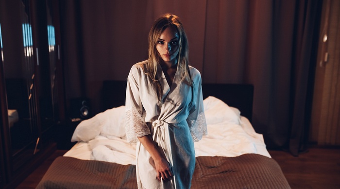 Woman in bathrobe standing in bedroom