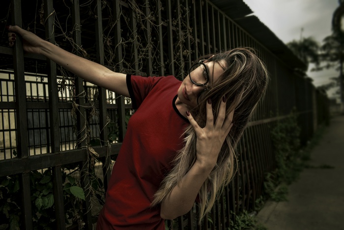 Woman with glasses leaning on a fence