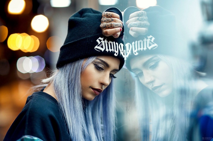 Woman with blue hair and tattoos wearing a hat