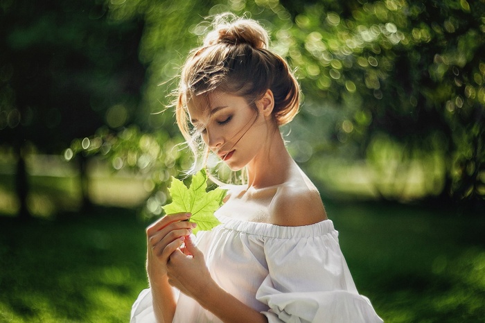 Woman holding a green leaf outdoors
