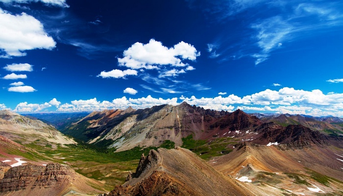Vast mountain range under a blue sky with clouds