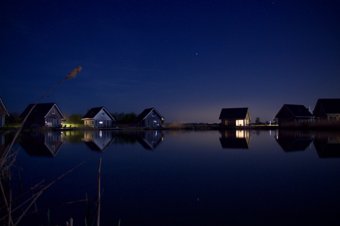Houses on a lake at night under a starry sky
