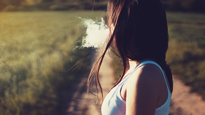 Woman exhaling smoke in a field