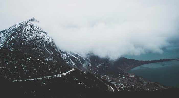 Snow-capped mountain overlooking a coastal town and sea