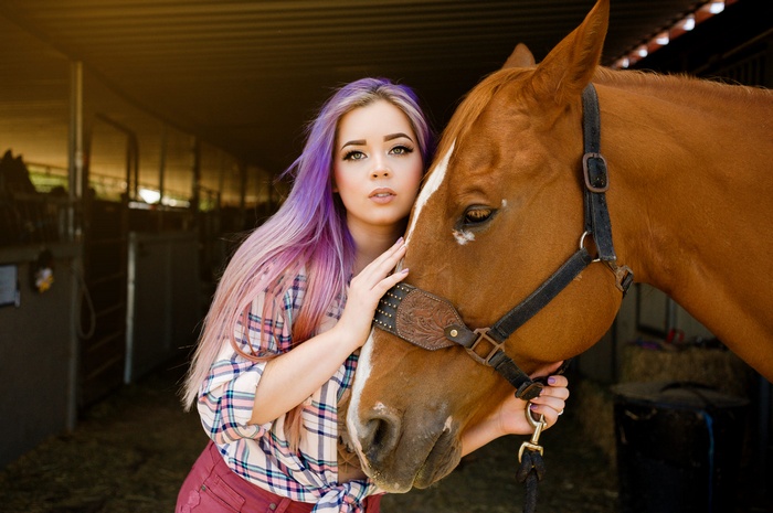 Woman with purple dyed hair and horse in stable