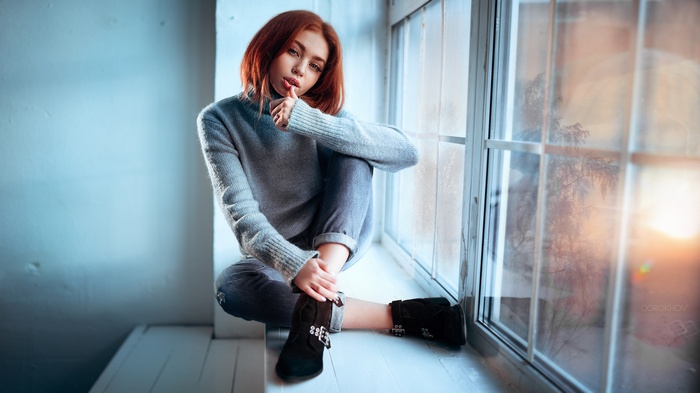 Woman in sweater sitting by the window