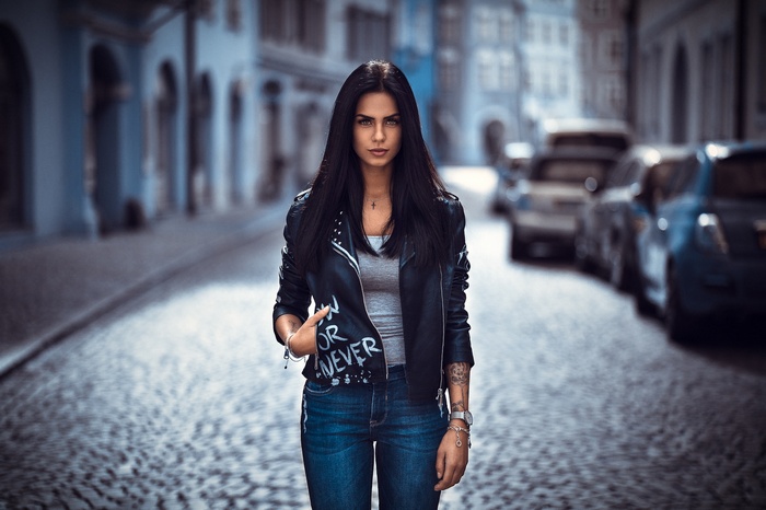 Woman in leather jacket and jeans on cobblestone street