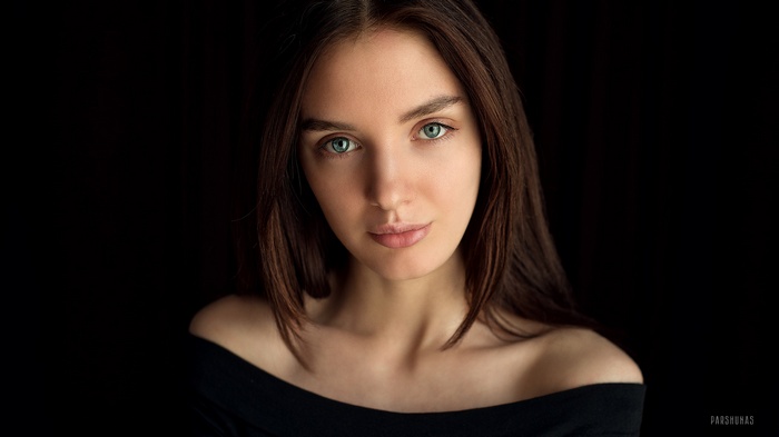 Woman with green eyes against a black background