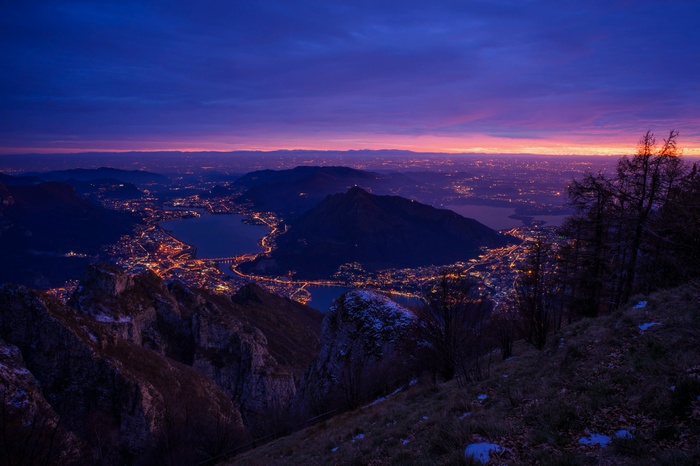 Cityscape at dusk with mountains and lakes