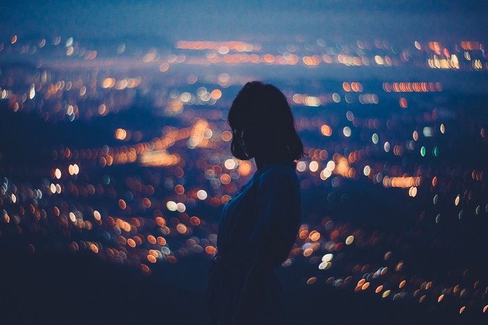 Silhouette of a woman against bokeh city lights