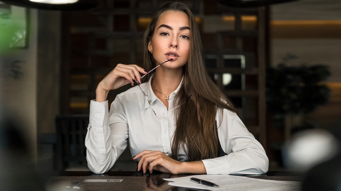 Woman in white shirt holding glasses