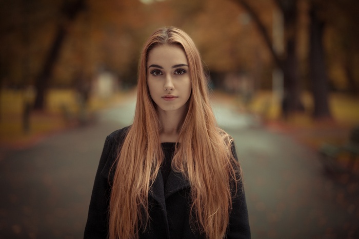 Woman with long blonde hair in a black coat outdoors