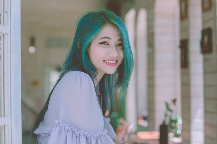 Young Asian woman with teal hair smiling