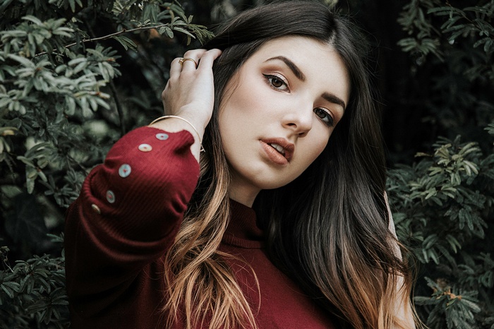 Woman with dark hair and makeup in a red sweater