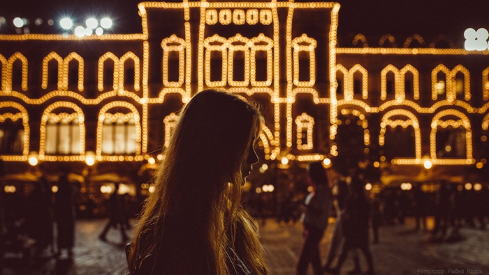 Woman in profile with illuminated building at night