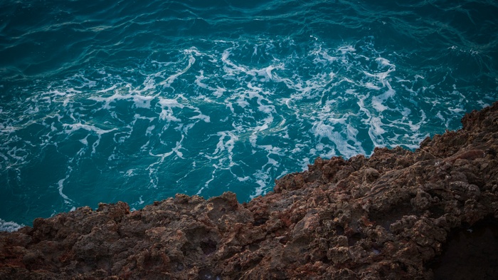 Turquoise ocean waves crashing on rocky shore