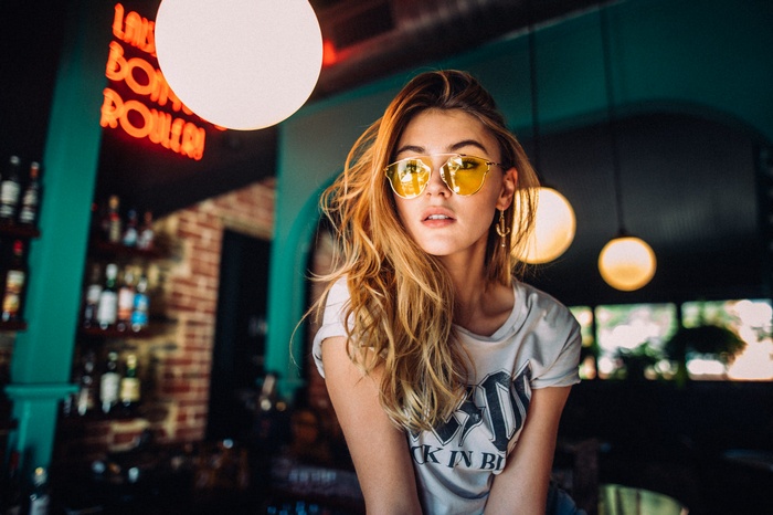 Woman with blonde hair and yellow sunglasses in a bar