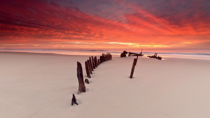 Shipwreck remains on a beach at sunset