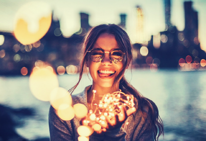 Woman holding fairy lights with city skyline