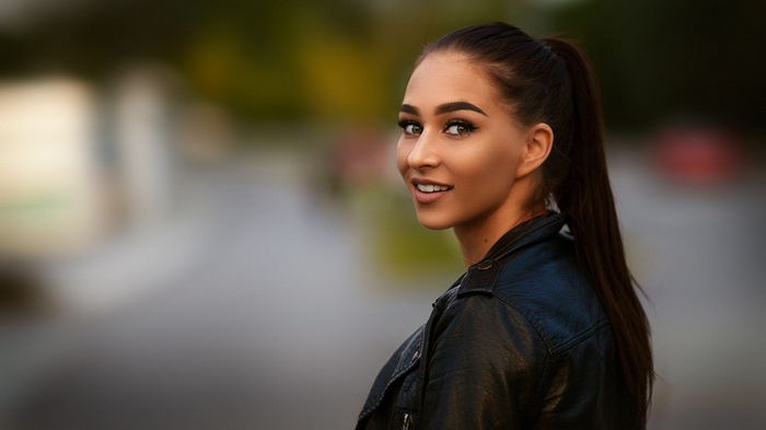 Woman with ponytail wearing leather jacket outdoors