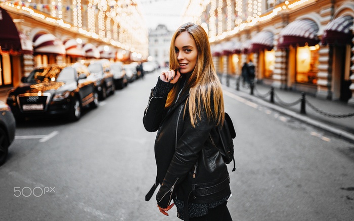 Woman in leather jacket on street with cars