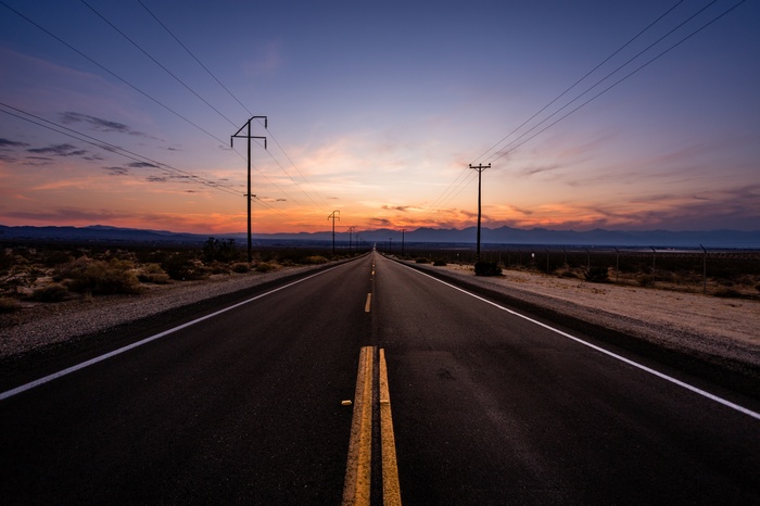 Desert road at sunset with power lines