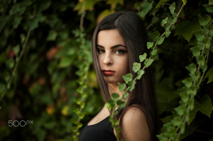 Woman posing behind ivy leaves