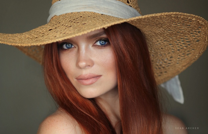Woman with red hair and blue eyes wearing a straw hat