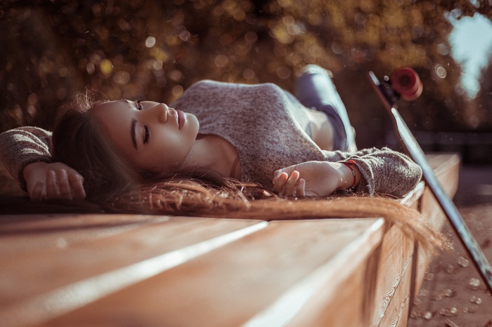 Woman lying on a bench with a skateboard