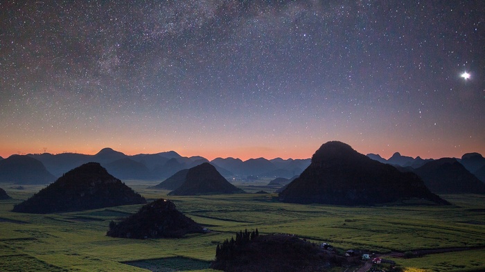 Starry night over conical hills and canola fields
