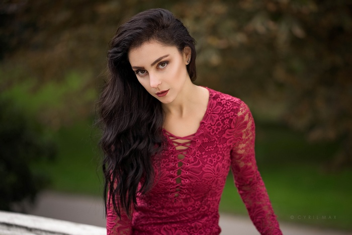 Woman with dark hair in a red lace dress outdoors