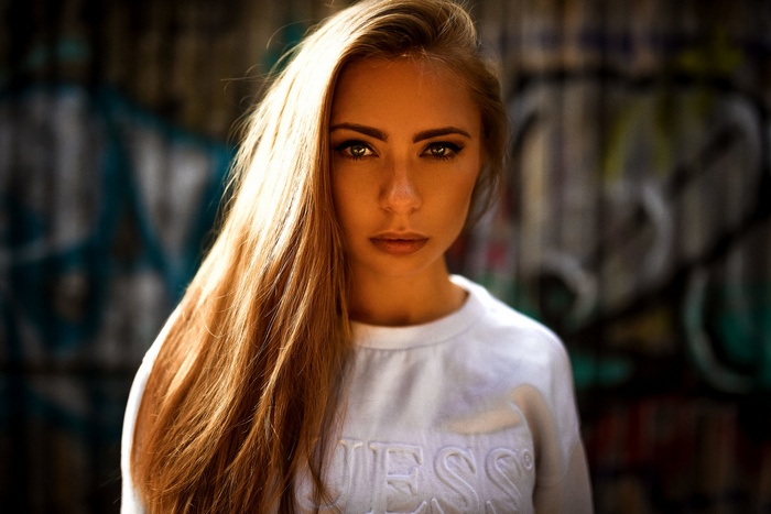Model with long hair wearing a white Guess sweatshirt