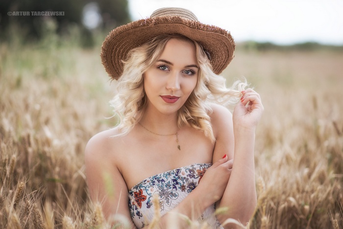 Woman with blonde hair and straw hat in a wheat field