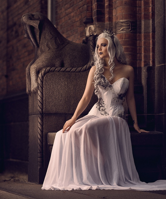 Woman in white dress with crown sitting on stone